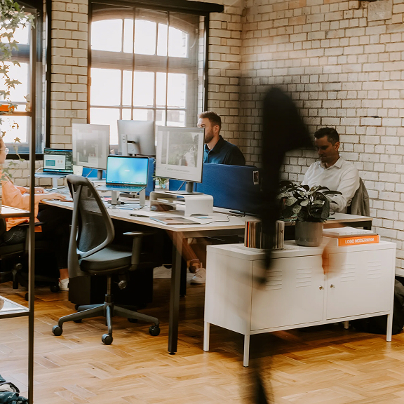 Two office workers sat at their computers in a modern openplan office environment