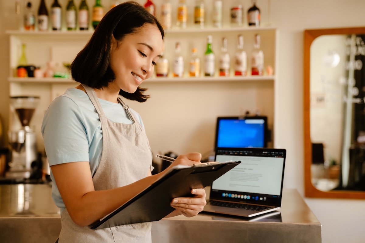 Local business owner barista woman writing down notes while working in cafe